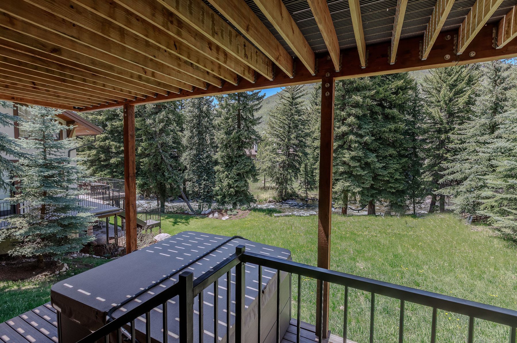 Covered lower patio with hot tub and creek view